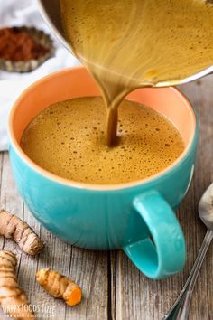 a cup of coffee being poured into it with ginger spice next to the mug and spoon