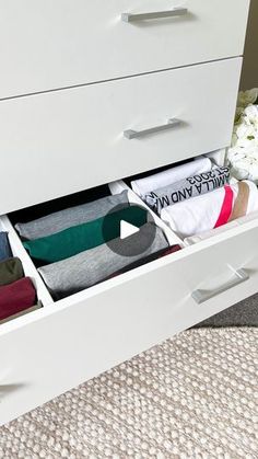 an open drawer with several pairs of socks in it and flowers on the floor next to it