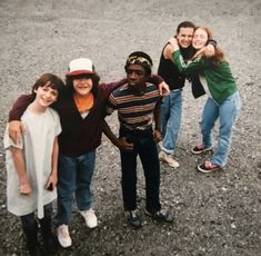 a group of young people standing next to each other on top of a dirt field