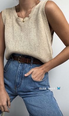 a woman wearing jeans and a sweater posing for the camera with her hand on her hip