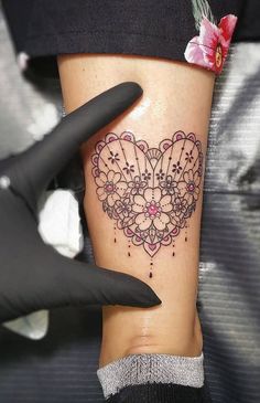 a woman's leg with a heart tattoo on her left side and pink flowers in the middle