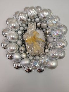 a christmas wreath with silver balls and a yellow bow on the front, against a white background