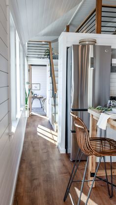 a kitchen and dining area in a tiny home with wood floors, white walls, and wooden stairs