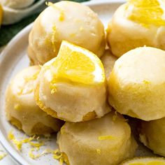 a white plate topped with lemon cookies covered in icing and sliced lemon wedges