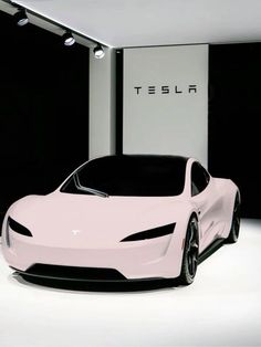 a pink car is parked in front of a wall with the tesla logo on it