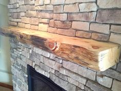 a fire place with a wooden shelf above it