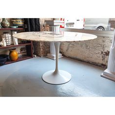 a white table sitting on top of a blue floor next to a window and shelves