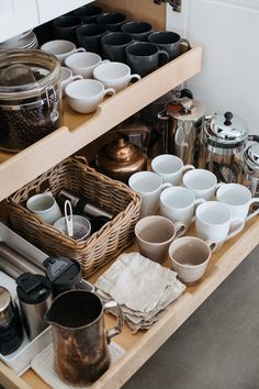 an organized kitchen drawer with coffee mugs and pots