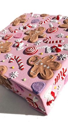 a pink wrapping paper with gingerbreads and candies on it, sitting on a white surface