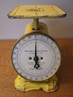 an old yellow kitchen scale sitting on top of a wooden table