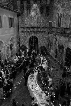 an aerial view of a dining hall with many people sitting at tables and lights strung from the ceiling