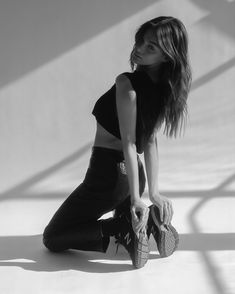 black and white photograph of a woman sitting on the ground with her shoes in hand