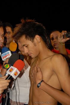 a shirtless man is surrounded by reporters and microphones