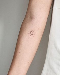 a woman's arm with a small sun and stars tattoo on her left arm