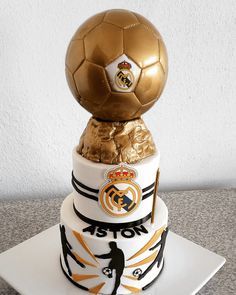 a three tiered cake with a soccer ball on top and gold foil wrapper