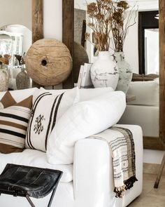 a living room filled with white furniture and lots of vases on top of it