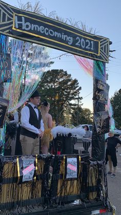 a man and woman standing on top of a float in the middle of a street