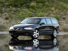 a black volvo wagon parked in front of a body of water