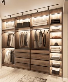 a walk in closet filled with lots of white and brown clothing hanging on wooden shelves