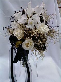 a vase filled with white and black flowers on top of a table covered in cloth