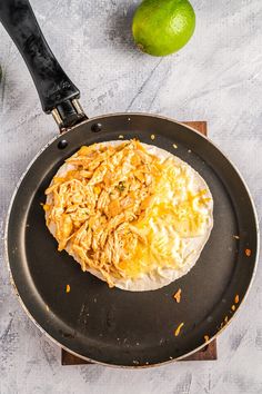 an omelet is being prepared in a skillet with limes around it