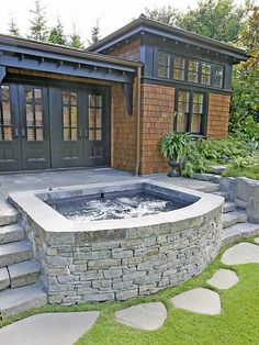 an outdoor hot tub in the middle of a garden with steps leading up to it