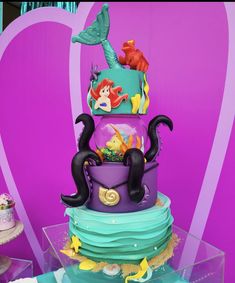 a three tiered cake decorated with ariel the mermaid and other disney characters on it