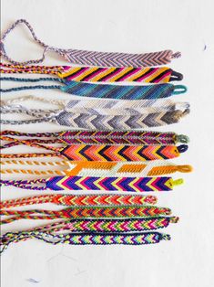 a bunch of different colored bracelets on a white surface with the string attached to them