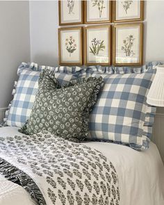 a bed with blue and white plaid sheets, pillows and pictures on the wall above it