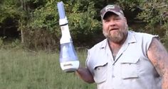 a man with a beard holding an electric toothbrush in his right hand and wearing a baseball cap