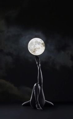 a woman is sitting on the ground with her hands up to the moon