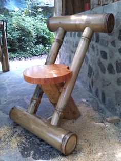 a wooden chair made out of logs sitting on the ground next to a stone wall