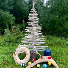 a christmas tree made out of driftwood in the grass next to a life preserver