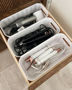 two white baskets filled with hairdryers on top of a wooden dresser next to a drawer