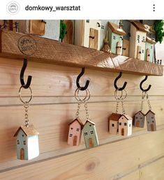 several small wooden houses hanging on a wall with key chains attached to them, along with other tiny house shaped objects