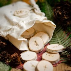 some wood slices and pine cones are on the table next to a bag with buttons