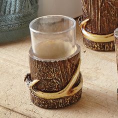 three wooden vases sitting on top of a table next to each other, one with a glass in it