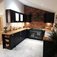 a kitchen with black cabinets and wooden counter tops is shown in this image, there is a potted plant next to the stove