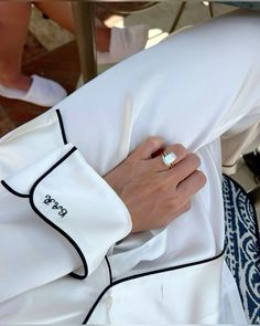 a close up of a person wearing a ring on their finger and holding onto a white shirt