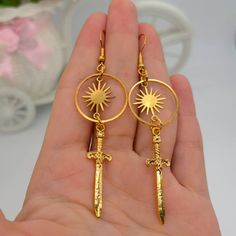 ♡ Sun Warrior Earrings ♡ Our Death Celestial Sword Earrings Are A Special Theme Of Deadly-And-Elegant Noble Beauty. Wear These Tiny Swords Cute Weapons, A Symbol Of War, Death And Conquests Throughout History On Your Ears As A Beautiful Sign Of Love And Peace. These Dangerous Sword Charms Capture The Timeless Beauty Of Your Outfit. They're also very comfy and lightweight. Pair them with a matching Victorian costume or take them out at parties where you want to be at the center of everyone's atte Sun Aesthetic Jewelry, Sun Themed Accessories, Sun Fantasy Outfit, Sun Earrings Aesthetic, Sun Themed Jewelry, Sun Themed Clothes, Sun Jewelry Aesthetic, Sun Themed Outfits, Fantasy Jewelry Earrings