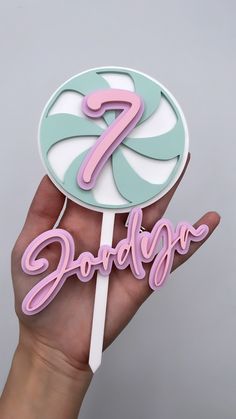 a hand holding a lollipop with the number seven on it's top