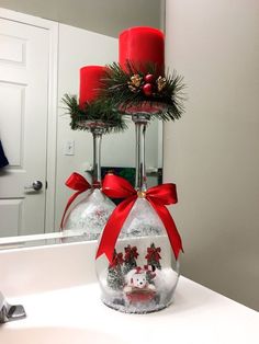 two wine glasses with christmas decorations on them sitting on a counter in front of a mirror