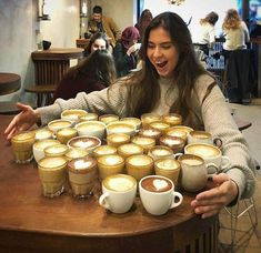 a woman sitting at a table with many cups of coffee