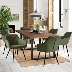 a dining room table with green chairs around it