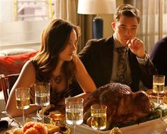 a man and woman sitting at a dinner table with a turkey in front of them