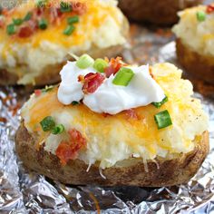 the baked potatoes are covered with sour cream and green onions on top, along with other toppings