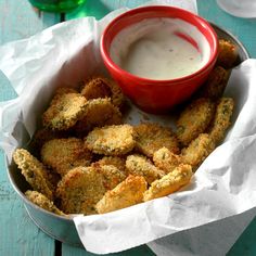 a basket filled with fried food next to a bowl of ranch dressing