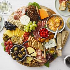 an assortment of cheeses, meats and crackers on a platter