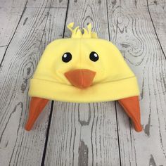 a yellow bird hat with black eyes on top of a wooden floor