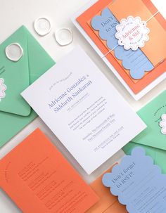 the wedding stationery is laid out on top of different colored envelopes and papers